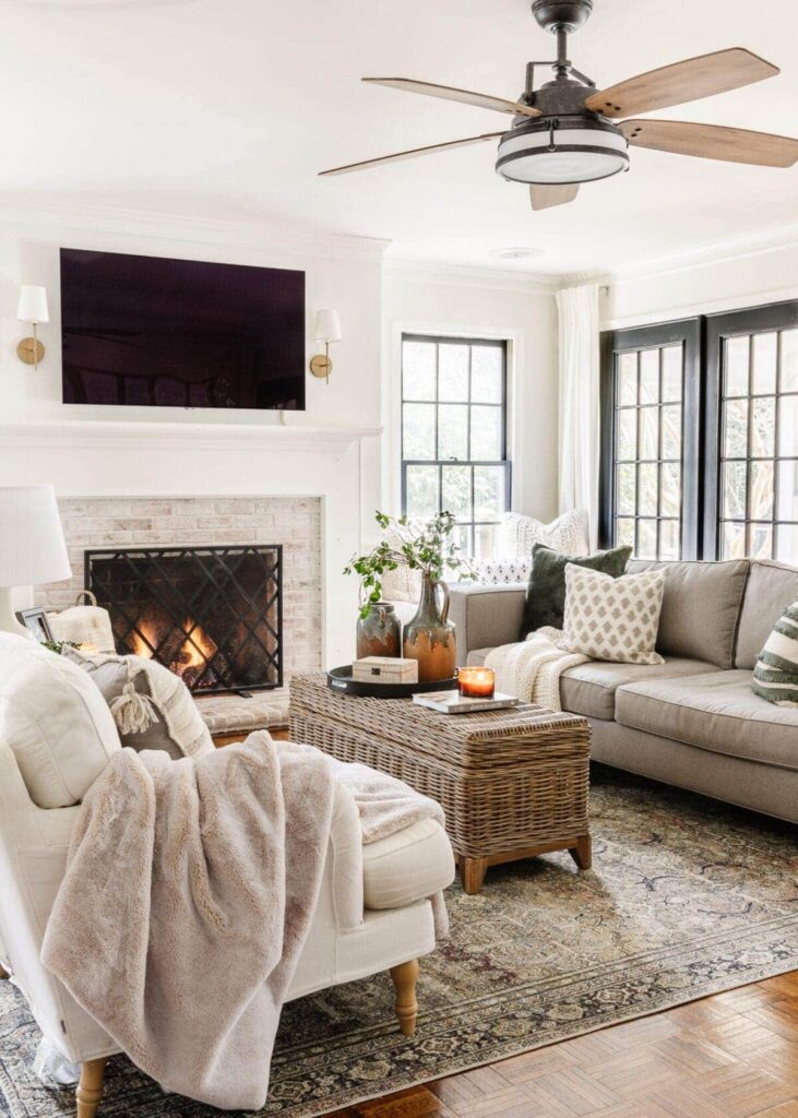 Neutral winter living room with fireplace, layered textiles, and warm wood accents creating a cozy and calm winter home reset.