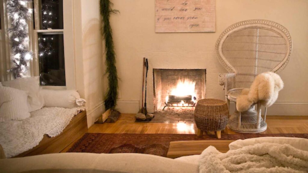 Soft winter bedroom with fireplace, neutral bedding, and warm ambient lighting, styled for a gentle winter home reset and slow living.