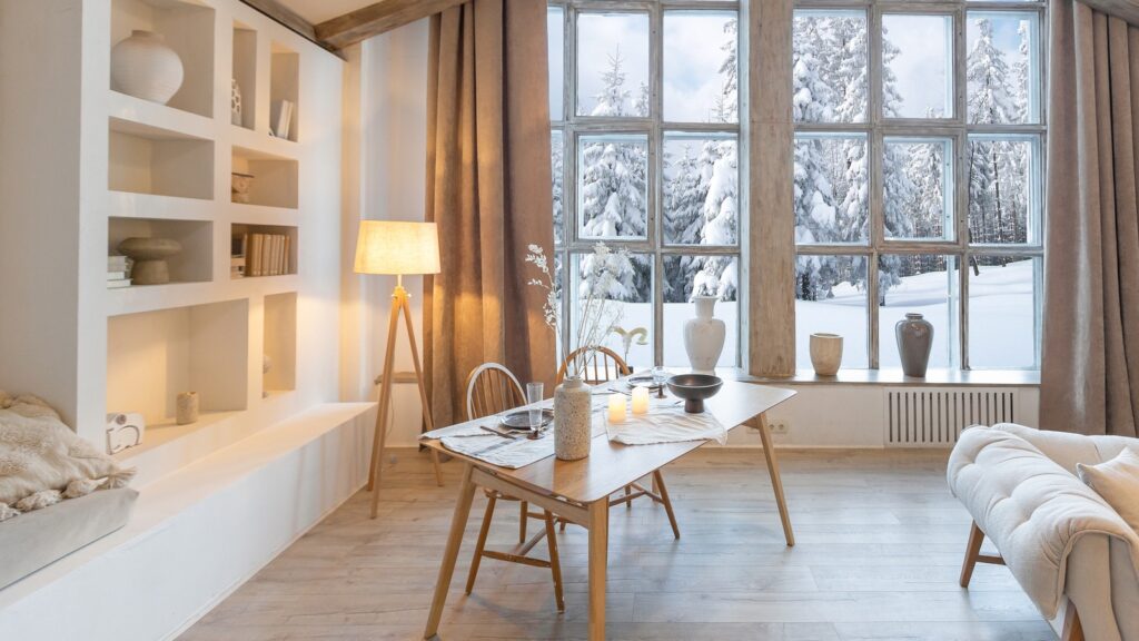 Light-filled winter dining space with neutral decor, soft lighting, and snowy views, styled for a calm and cozy winter home reset.